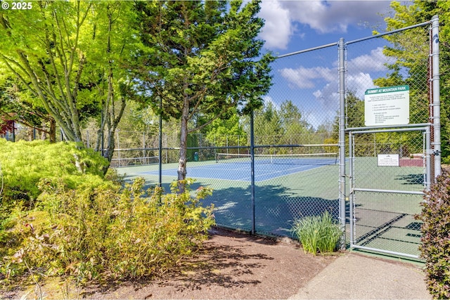 view of tennis court with a gate and fence
