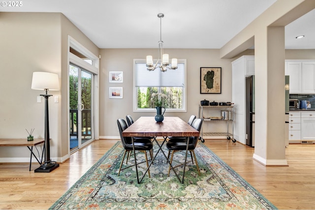 dining area with light wood finished floors, a chandelier, and baseboards