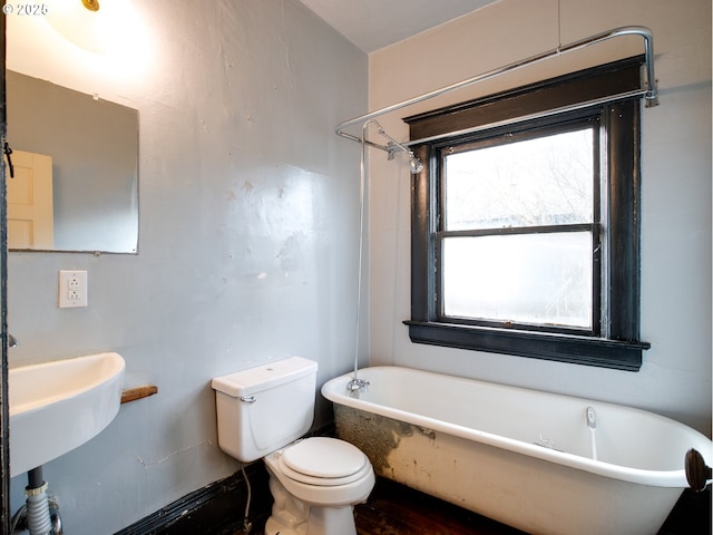 bathroom with a tub to relax in and toilet