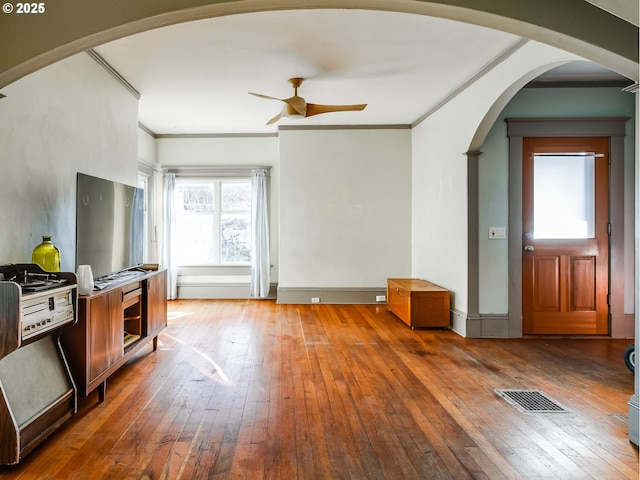 unfurnished living room with hardwood / wood-style floors, ornamental molding, and ceiling fan