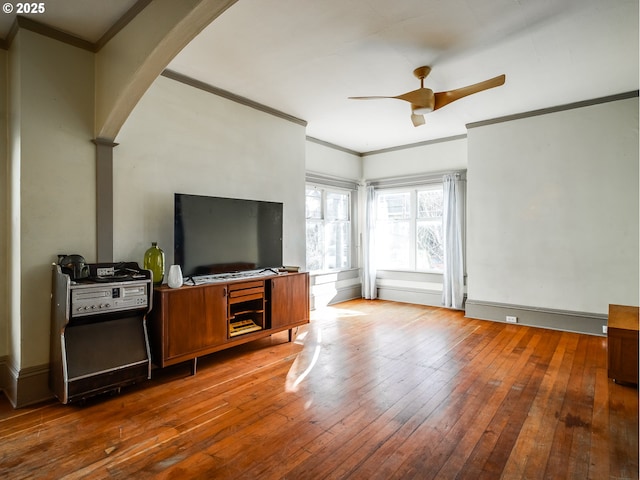 living room featuring ceiling fan, ornamental molding, and wood-type flooring