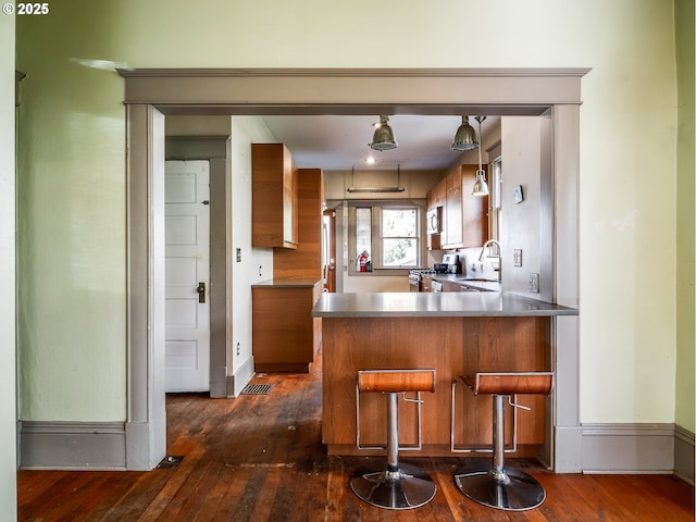 kitchen featuring gas range, dark hardwood / wood-style floors, sink, and kitchen peninsula