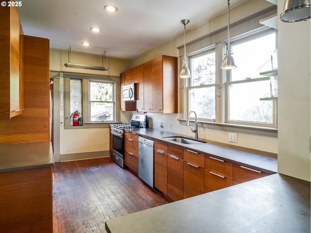 kitchen featuring appliances with stainless steel finishes, dark hardwood / wood-style floors, sink, and hanging light fixtures