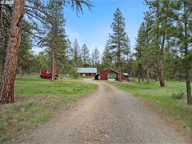 view of front facade with dirt driveway, a detached garage, and an outdoor structure