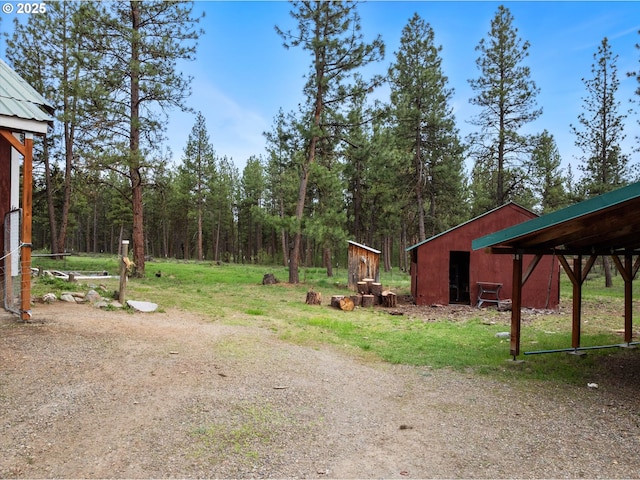 view of yard featuring a pole building, an outdoor structure, and a view of trees