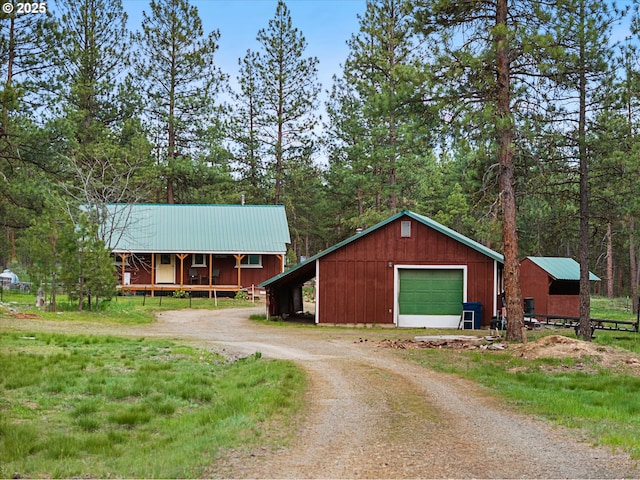 view of front of home featuring driveway, an outbuilding, a garage, and metal roof