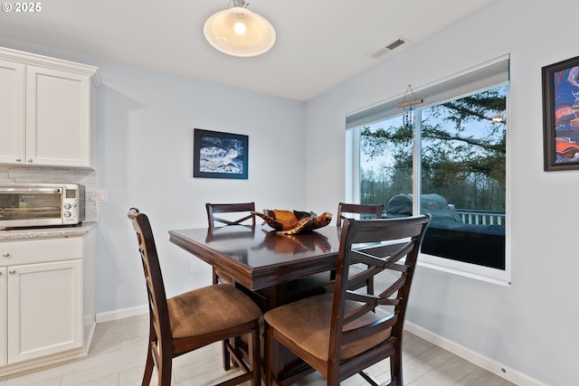 dining room featuring baseboards, visible vents, light wood-type flooring, and a toaster