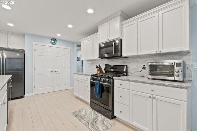 kitchen featuring recessed lighting, a toaster, backsplash, white cabinets, and appliances with stainless steel finishes