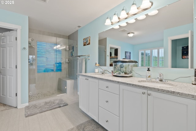 full bathroom with double vanity, a sink, visible vents, and a shower stall