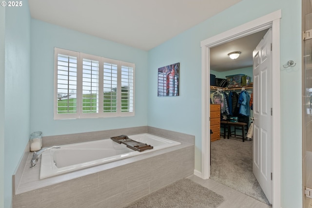 bathroom featuring a spacious closet and a bath