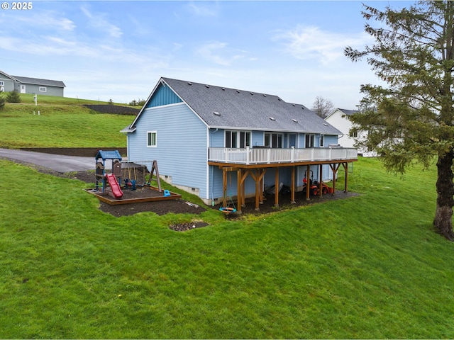 back of house featuring roof with shingles, a deck, and a yard