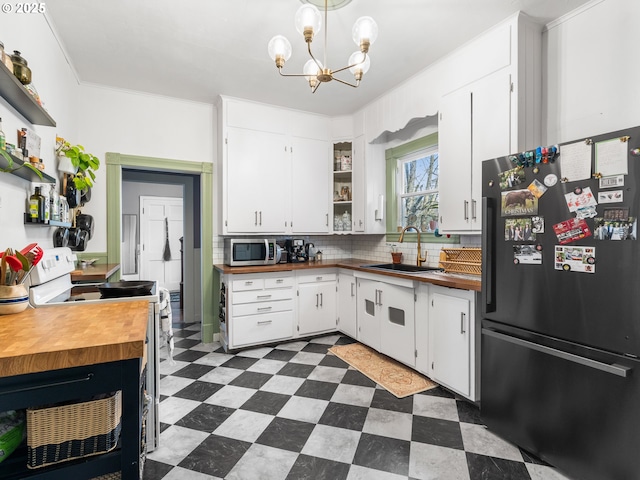 kitchen with tasteful backsplash, white cabinetry, sink, black fridge, and electric stove