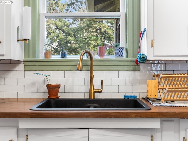 details featuring tasteful backsplash, sink, and white cabinets