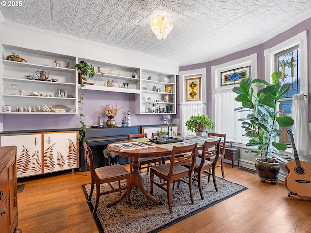 dining space with hardwood / wood-style flooring, built in features, and ornamental molding