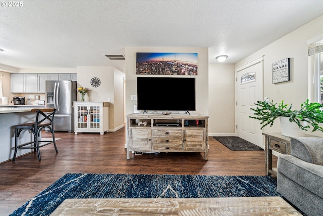 living room with dark wood-style flooring, a textured ceiling, and baseboards