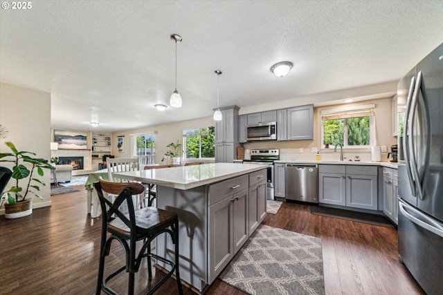 kitchen with appliances with stainless steel finishes, gray cabinetry, a sink, a textured ceiling, and light countertops