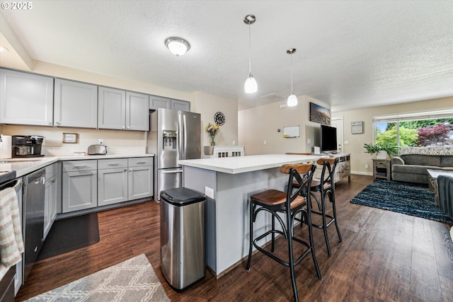 kitchen with stainless steel refrigerator with ice dispenser, gray cabinetry, open floor plan, dark wood-style floors, and a textured ceiling