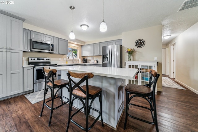 kitchen featuring appliances with stainless steel finishes, gray cabinets, light countertops, dark wood finished floors, and a textured ceiling
