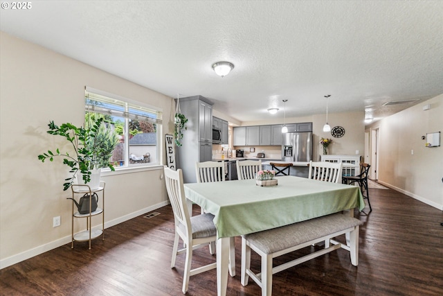 dining area featuring dark wood finished floors, a textured ceiling, and baseboards