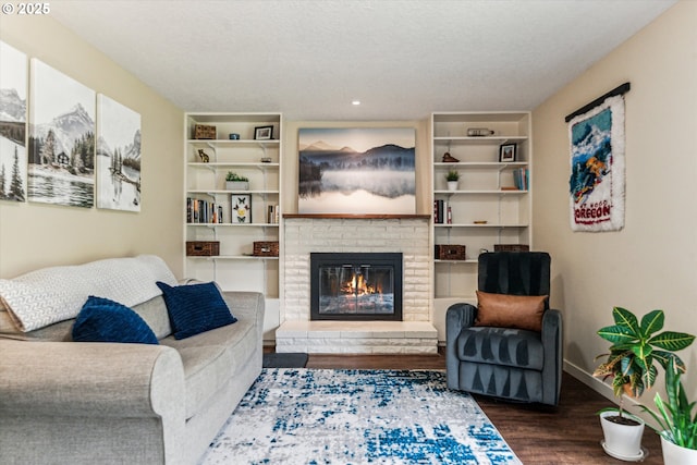 living area featuring wood finished floors, a brick fireplace, baseboards, and recessed lighting
