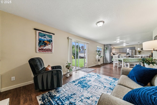 living room featuring baseboards, dark wood-type flooring, and a textured ceiling