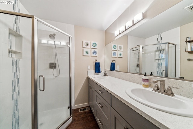 full bath with a stall shower, wood finished floors, double vanity, and baseboards