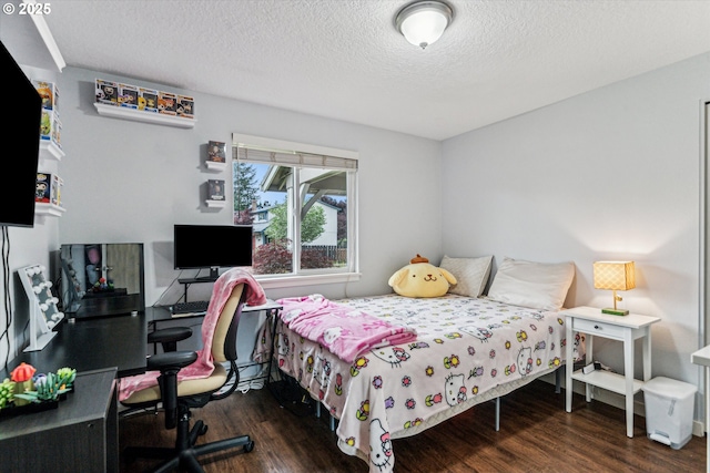 bedroom with wood finished floors, a textured ceiling, and an office area