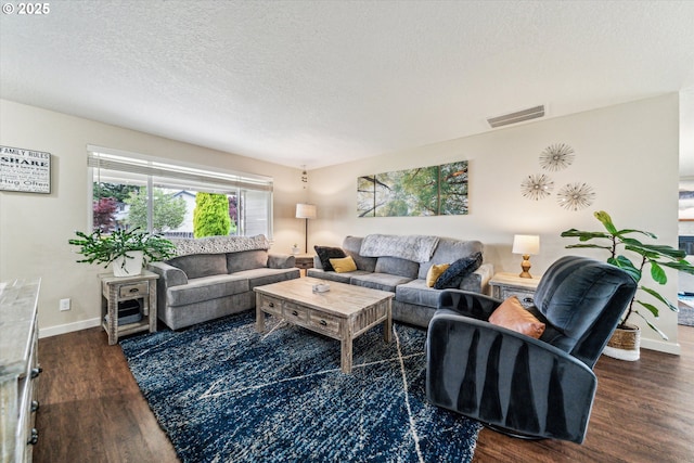 living room featuring dark wood-type flooring, a textured ceiling, and baseboards