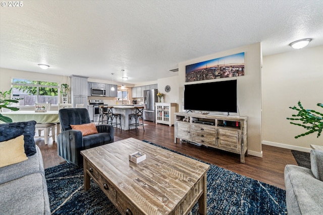living area featuring a textured ceiling, baseboards, and dark wood finished floors