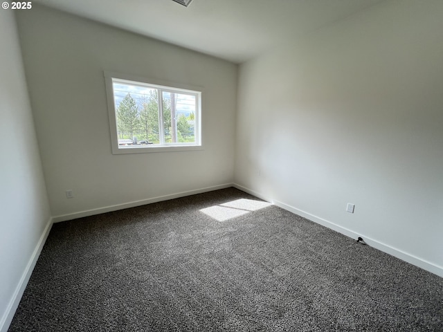 unfurnished room with baseboards and dark carpet
