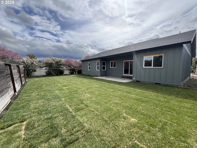 back of house featuring a shingled roof, board and batten siding, a patio area, and a fenced backyard