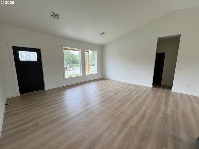 unfurnished living room featuring baseboards, visible vents, light wood finished floors, and lofted ceiling