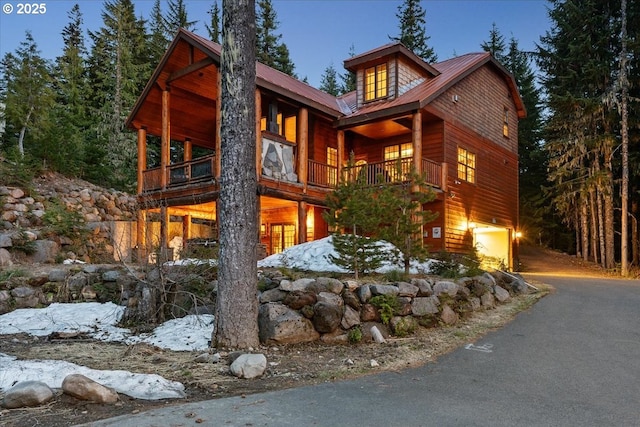 view of front facade with asphalt driveway, an attached garage, and metal roof
