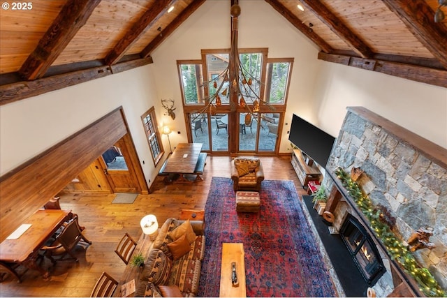 living area featuring a lit fireplace, wood ceiling, high vaulted ceiling, beamed ceiling, and wood-type flooring