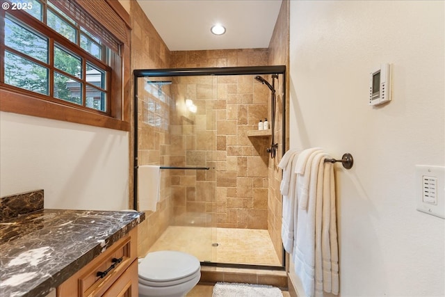 full bathroom featuring a shower stall, toilet, and vanity