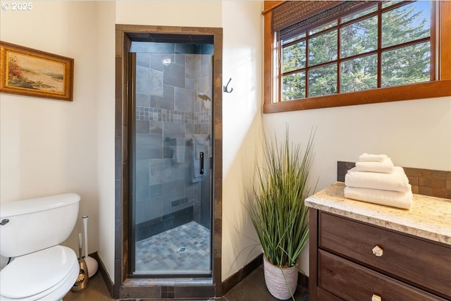 bathroom with a stall shower, toilet, baseboards, and vanity