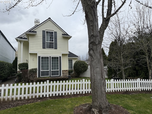 traditional-style house featuring a fenced front yard and a chimney