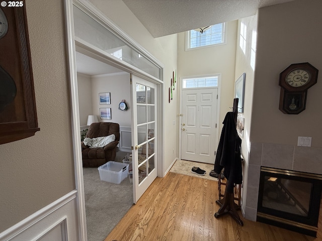 entryway featuring ornamental molding, light wood finished floors, and a tile fireplace