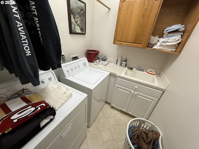 laundry room featuring light tile patterned floors, cabinet space, a sink, and separate washer and dryer