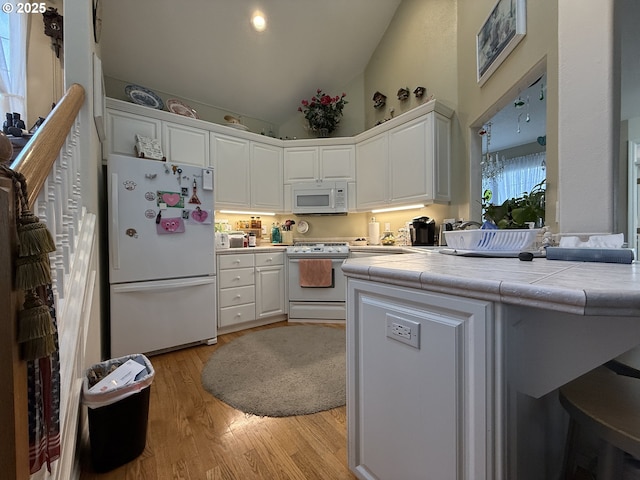 kitchen featuring white appliances, light wood-type flooring, tile counters, and white cabinets