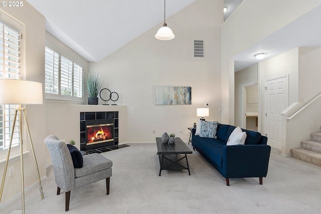 living room with visible vents, carpet flooring, a fireplace, and high vaulted ceiling