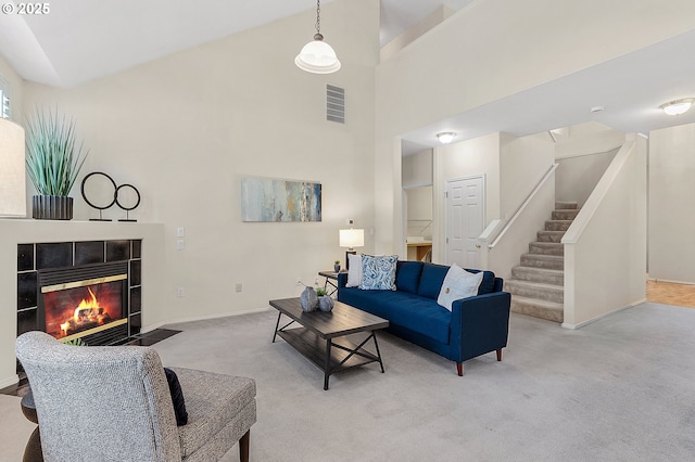 living room featuring visible vents, carpet, a fireplace, baseboards, and stairs