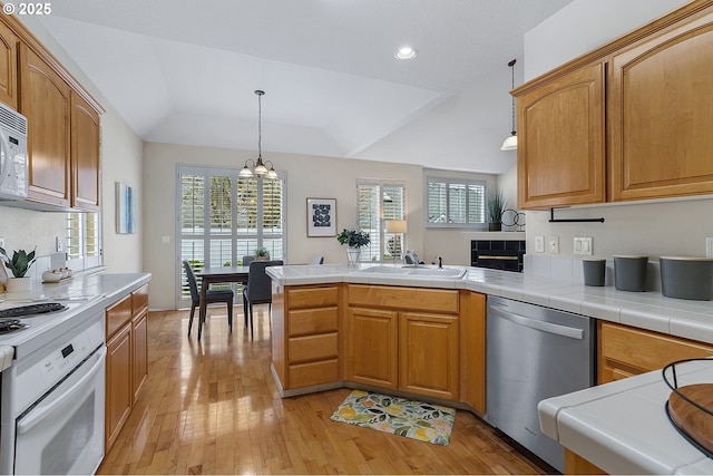 kitchen featuring a sink, stainless steel dishwasher, a peninsula, range, and a chandelier