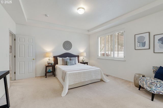 carpeted bedroom with baseboards and a raised ceiling