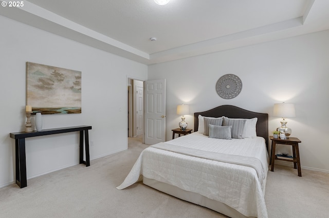 carpeted bedroom featuring a tray ceiling and baseboards