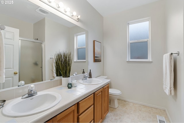 full bathroom with double vanity, visible vents, a stall shower, and a sink