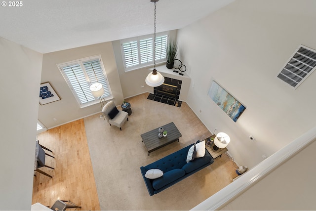 carpeted living area featuring visible vents, baseboards, and a tile fireplace