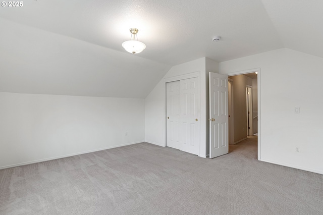 additional living space with baseboards, lofted ceiling, and carpet floors