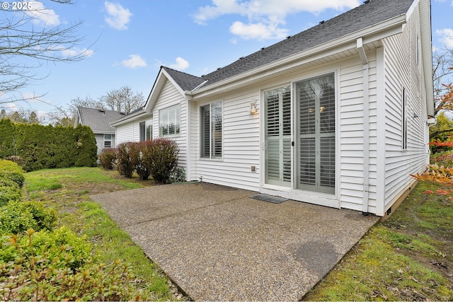 back of house with a shingled roof and a patio