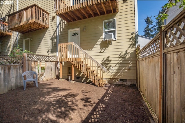 view of exterior entry with fence, cooling unit, a balcony, and crawl space
